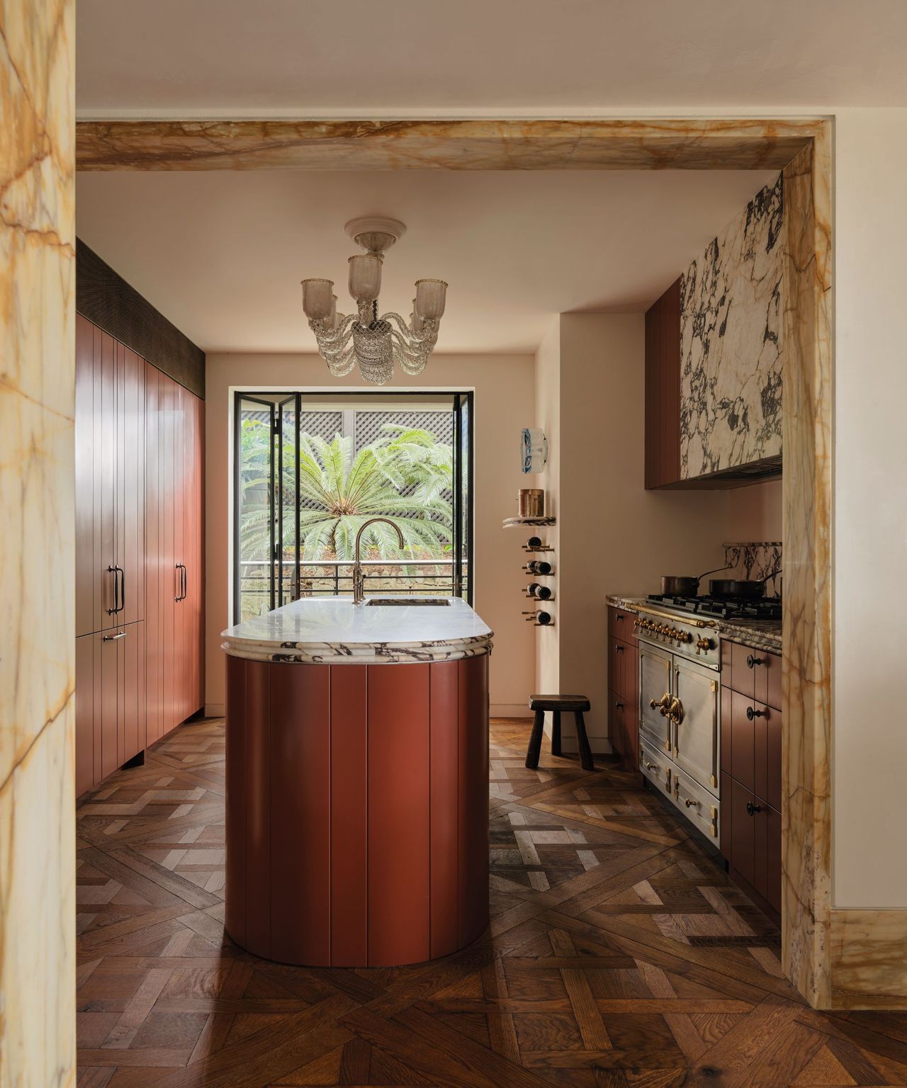 Kitchen with wooden flooring and rust coloured curved kitchen island and marble details