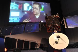 Rosetta Project Scientist Matt Taylor discusses the wake-up of the comet-chasing spacecraft (a model is seen in foreground) live on ESA TV at the agency's Space Operations Center in Darmstadt, Germany on Jan. 20, 2014.