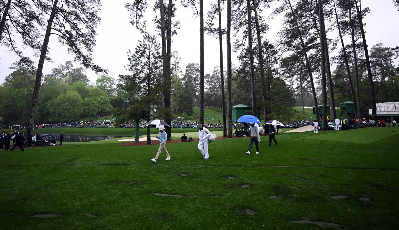 A golfer looks at the damage on the turf after three trees fell on it