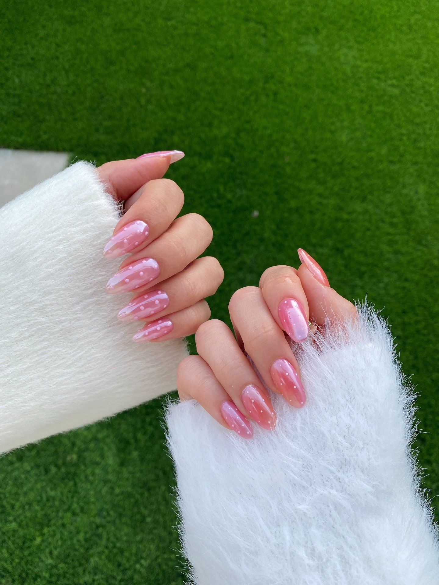 A person with pink glazed polka dot nails.