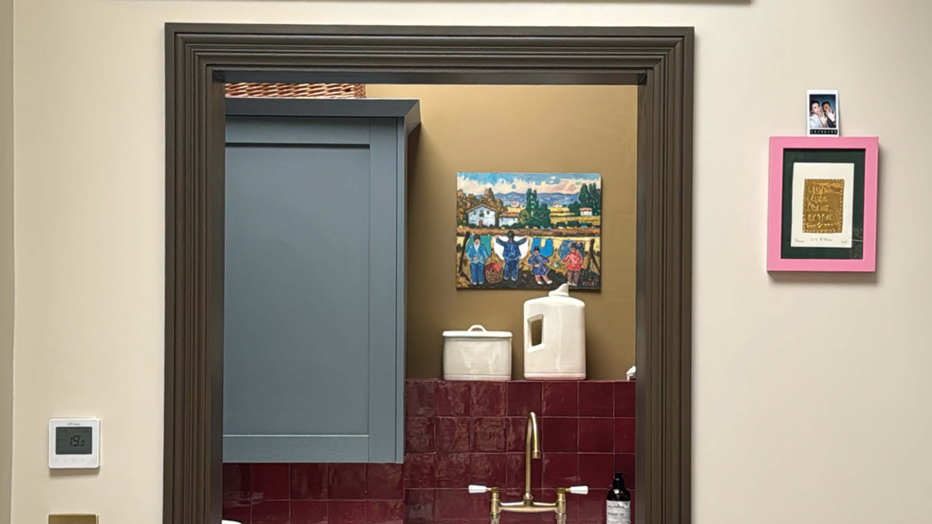 looking through the door at a kitchen with framed art placed on the wall 