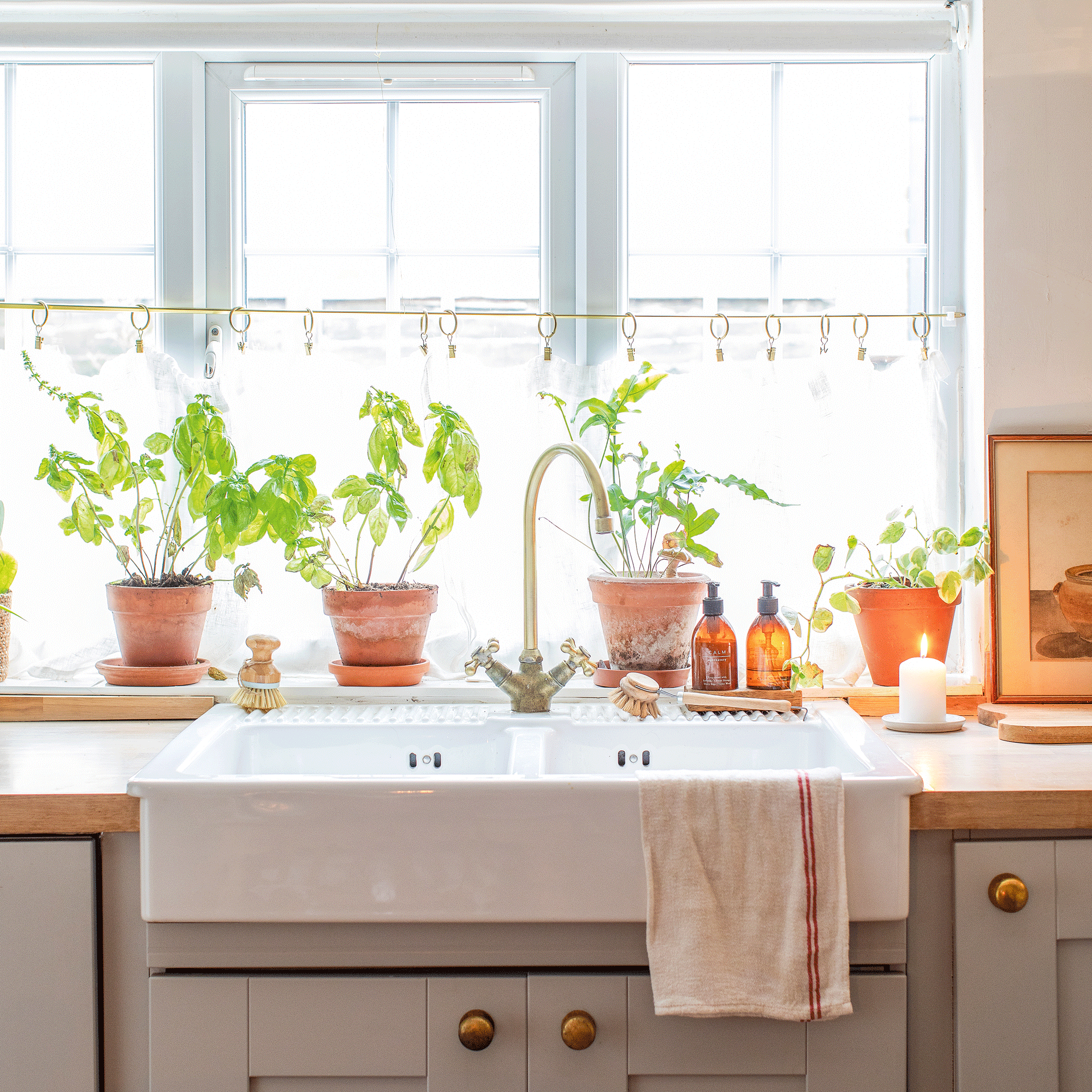 a kitchen with a Belfast sink and a cafe curtain in the window