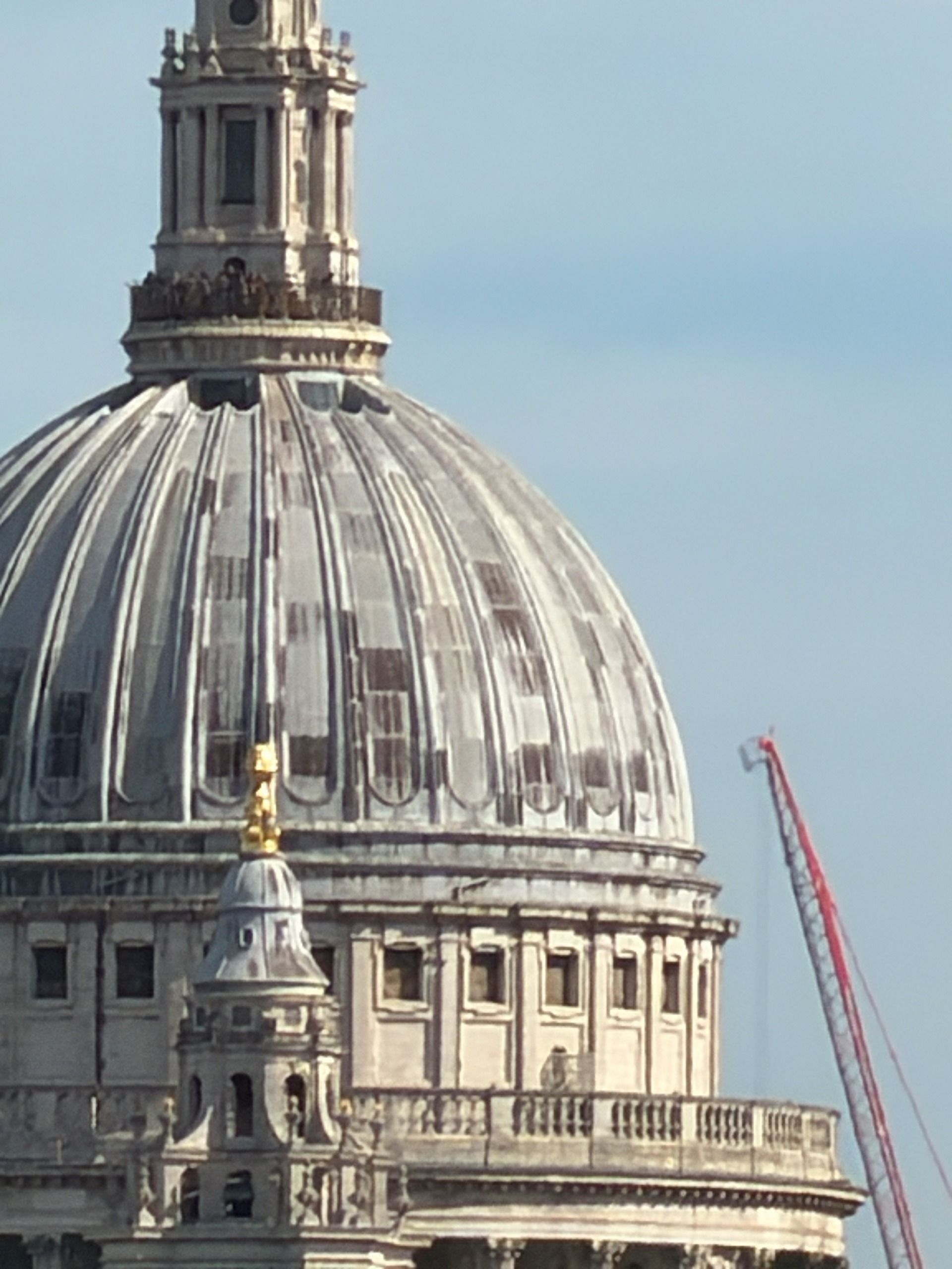 Telephoto close-up of the dome of St Paul&rsquo;s Cathedral with a construction crane visible beside it.