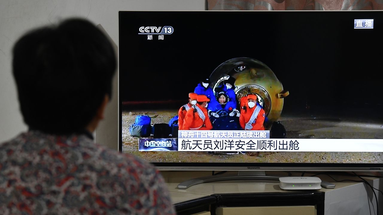 Citizens watch a live TV broadcast of the re-entry module of the Shenzhou 14 manned spacecraft landing at Dongfeng Landing field in Fuyang city, Anhui province, China, December 4, 2022.
