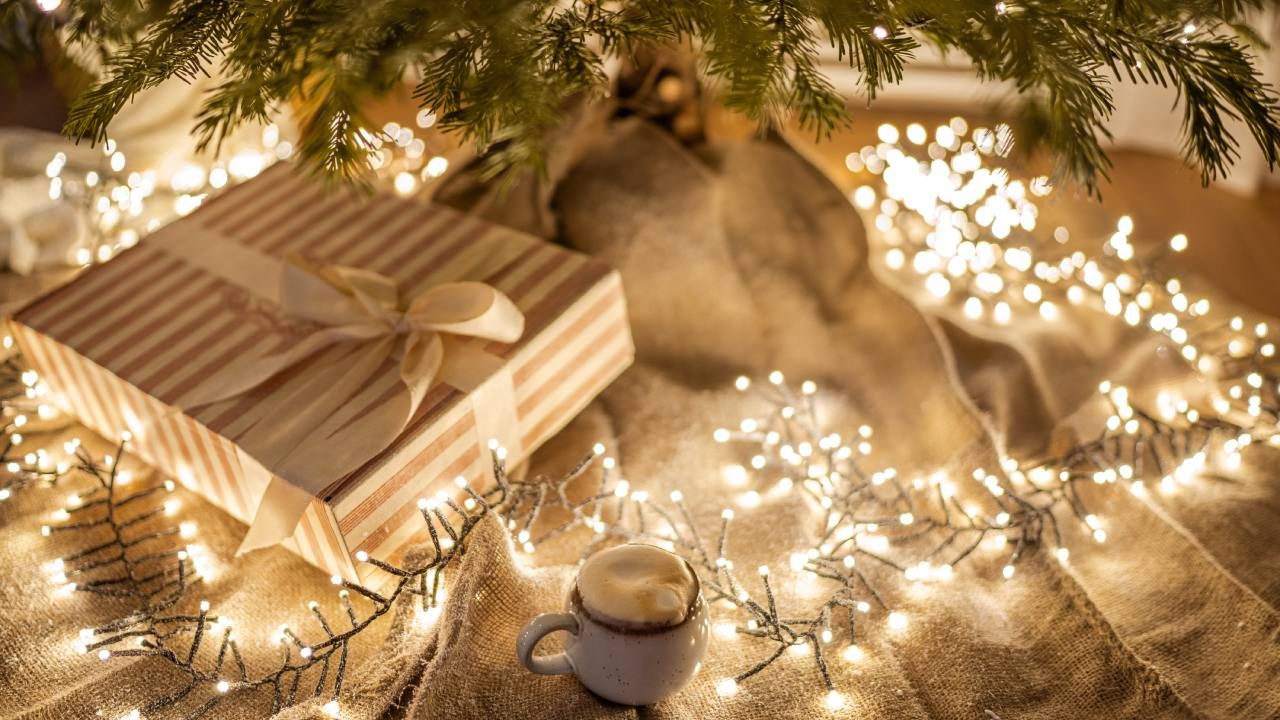 A string of yellow Christmas lights wrapped around presents under the Christmas tree