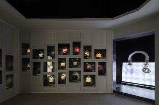 A shadowed room featuring handbags in illuminated frames in the walls