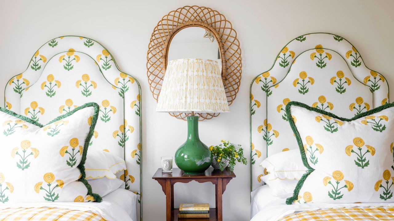 Twin beds with matching floral bedding and headboards, with a nightstand between them featuring a tall lamp