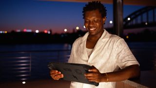 Acer Nitro Blaze 11 being held by a dark-skinned man in a white shirt standing in front of the water