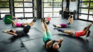 People performing hollow hold isometric abs exercise