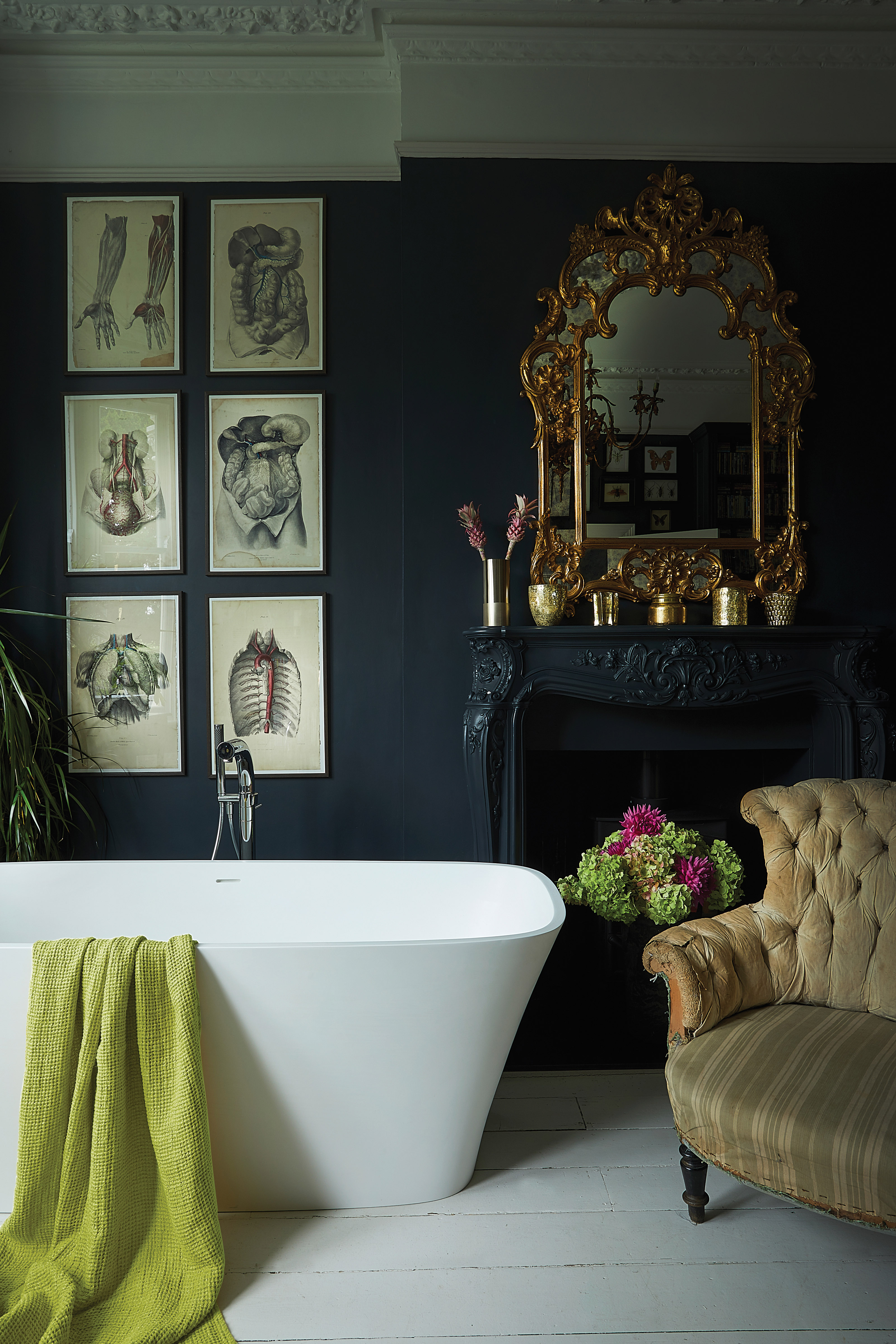 dark scheme bathroom with large white freestanding bath, ornate fireplace and gallery wall