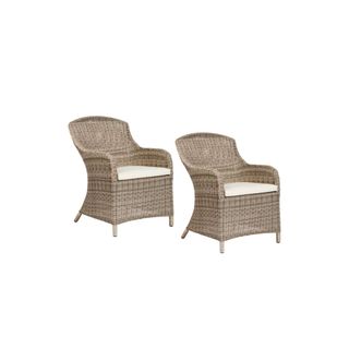 A pair of rattan garden chairs with cream cushions