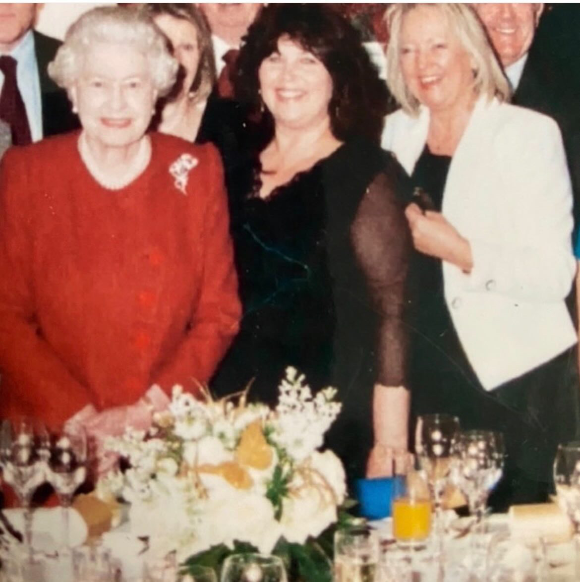 Queen Elizabeth, Stella McLaren and Angela Kelly posing in front of a table