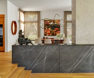 view to dining room and artwork over dark marble half wall