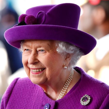 Queen Elizabeth wearing a purple coat and hat with an amethyst brooch