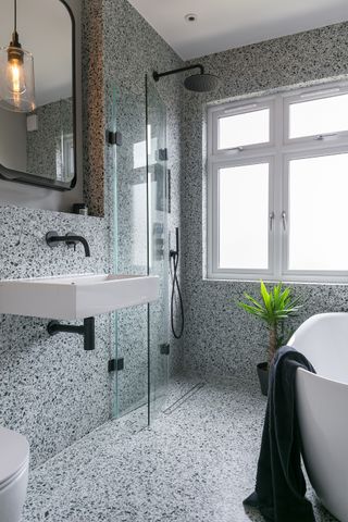 small bathroom with small bath and folding shower door by BC Designs