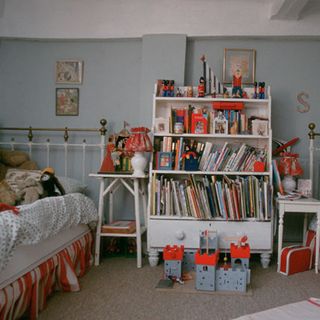 kids bedroom with grey wall bed white shelve books and toys