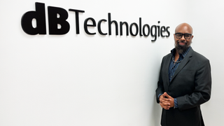 Smiling Darrin Young in a suit in front of the dBTechnologies sign.