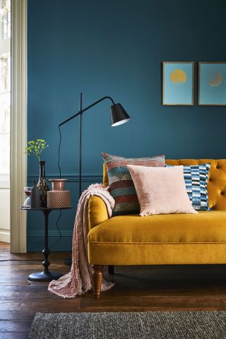 A living room with deep blue navy wall paint decor and mustard yellow sofas