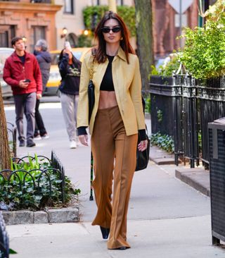 Emily Ratajkowski styles a butter yellow jacket with light brown trousers.