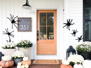 White front porch with large spiders and mums and spooky signage