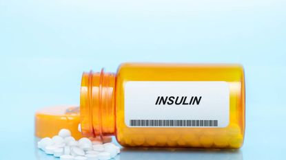 Pill bottle labeled "Insulin" lying on its side with pills spilling out.