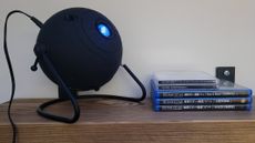 Photo of the Sega Toys Homestar Flux on a shelf next to some compatible projection discs