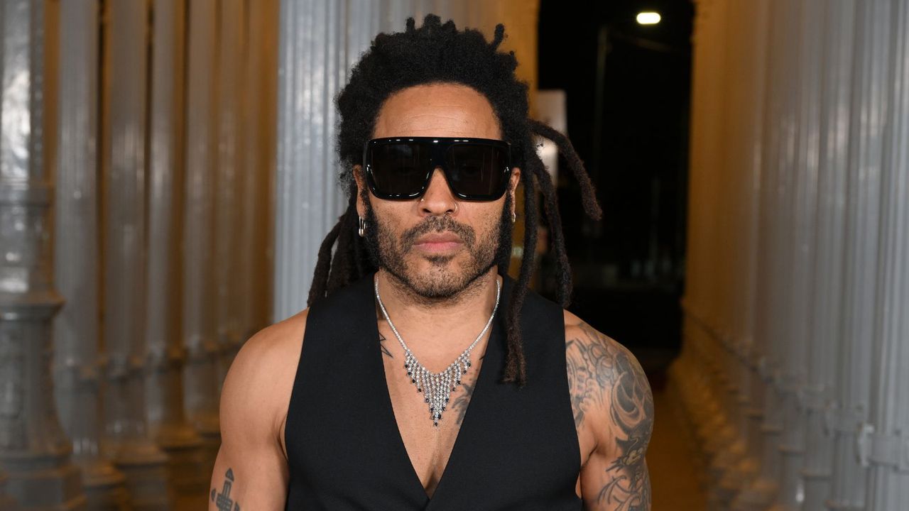 lenny kravitz wearing sunglasses on a gray background