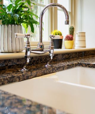 A white sink on a granite countertop, next to a windowsill