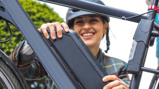 Woman attaching battery to e-bike outdoors