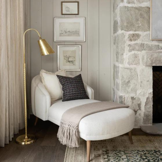 A gold floor lamp next to a chaise