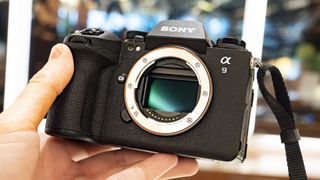Sony A9 III in the hand without lens and light reflecting off the camera's sensor