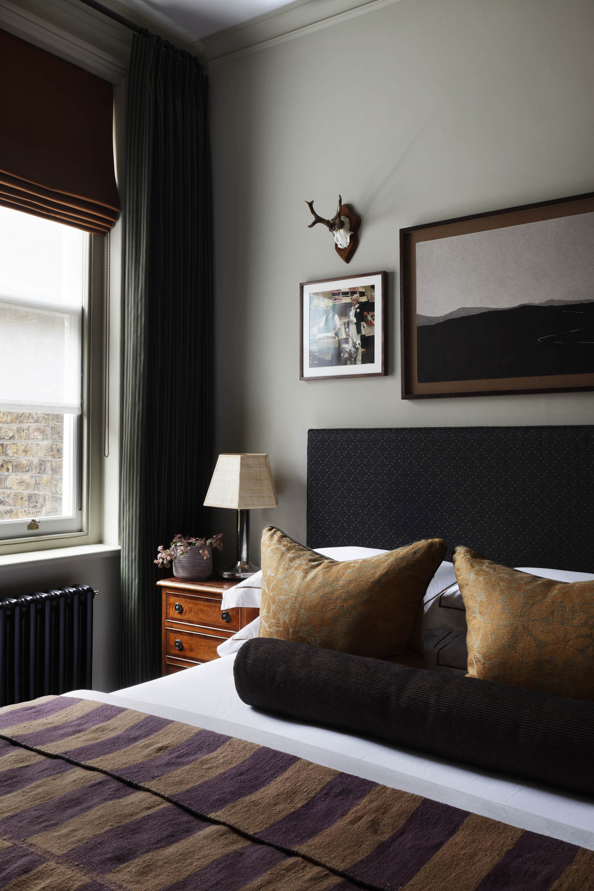 Christian Bense designed bedroom with dark textiles and art on the wall behind the bed