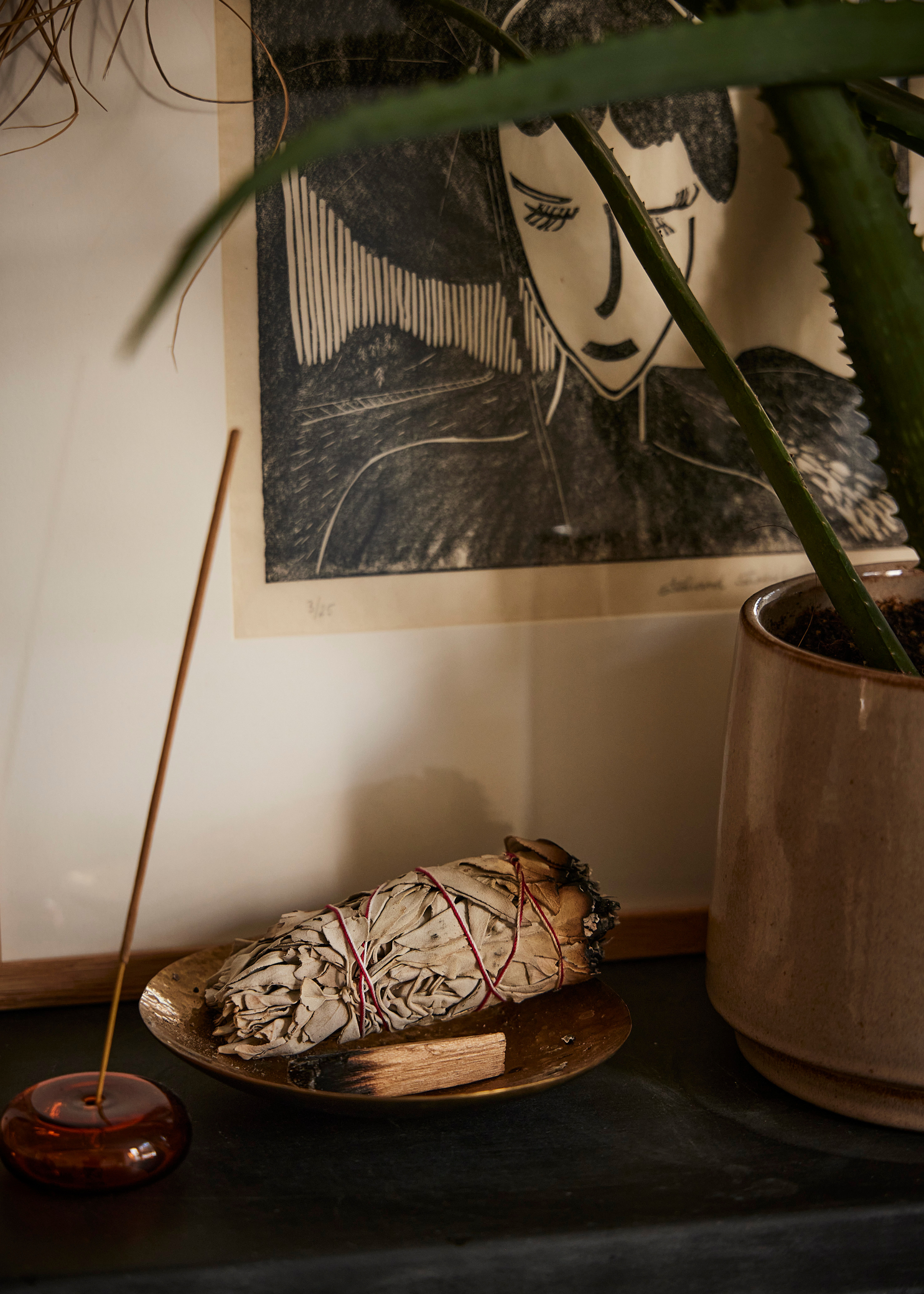 A close-up of an incense holder and a bowl of sage with palo santo