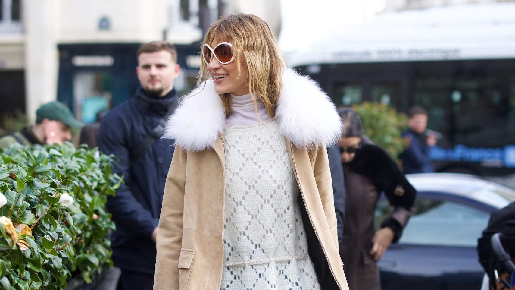 Bella Hadid wearing a tan coat, cream sweater, cropped flare jeans, socks, and loafers in Paris during PFW F/W 26.