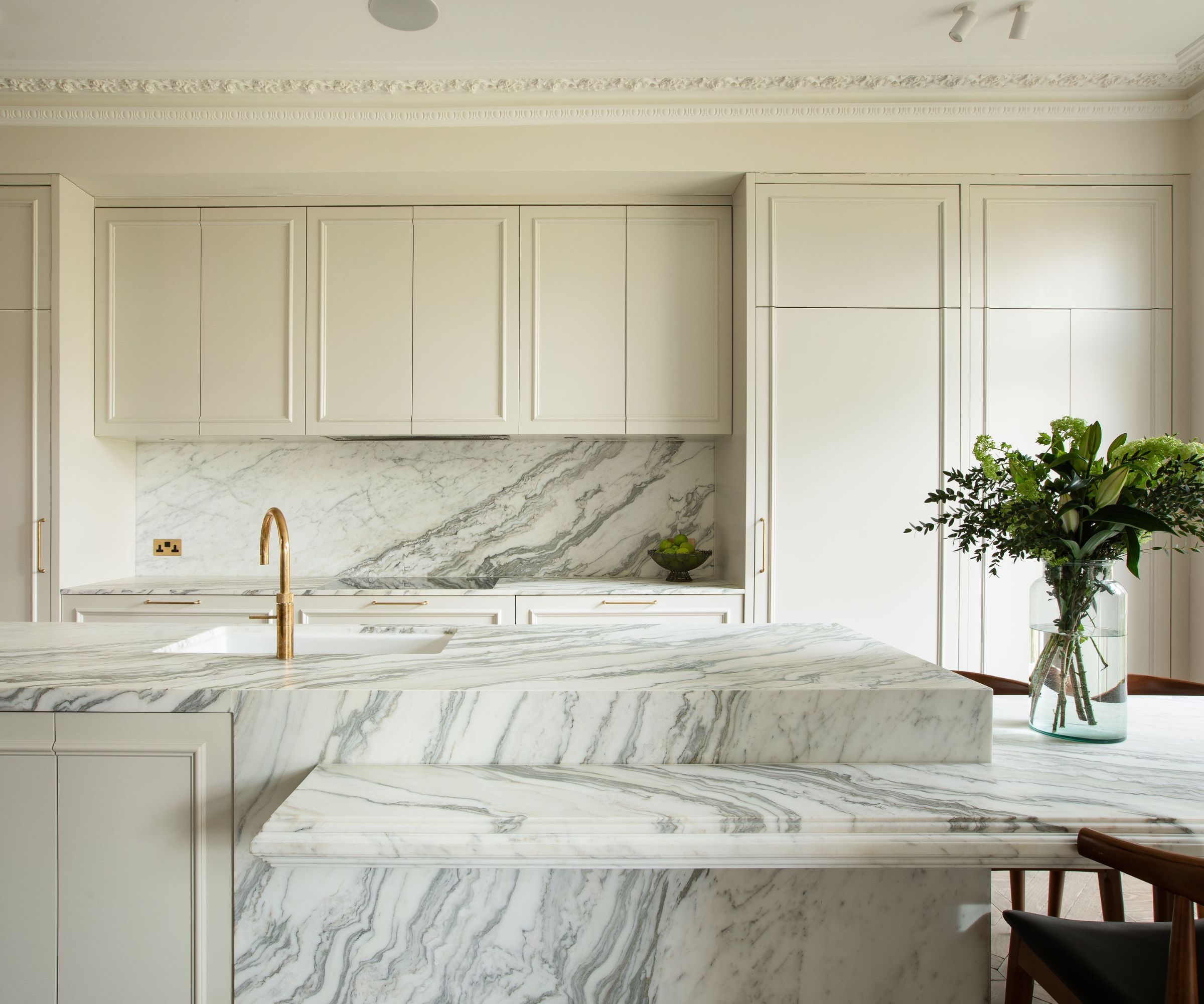 A neutral kitchen with cream cabinets and marble countertops