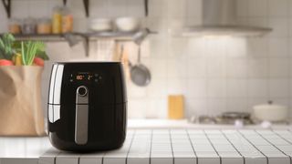A black air fryer on an open countertop in a kitchen