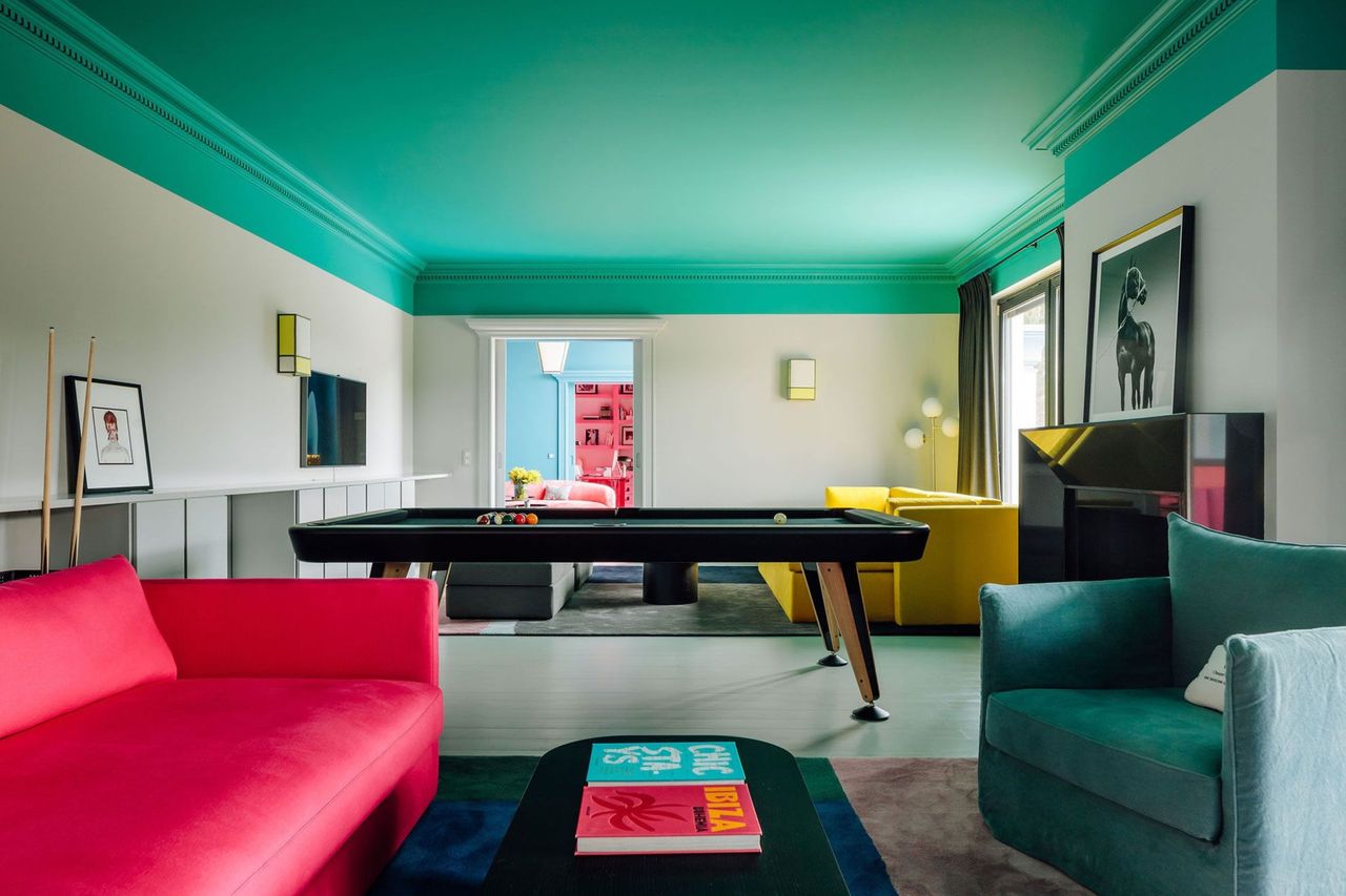 a room with high contrast green ceiling with a yellow and red sofa