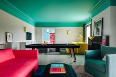 a room with high contrast green ceiling with a yellow and red sofa