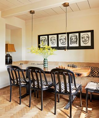 dining area with wooden table, black chairs with batik upholstery, corduroy bench, monochrome gallery wall and small brass pendant lights