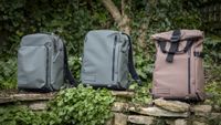 light green camera backpacks against wooden greenery background