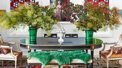 colorful dining room with black oval table, cowhide bench and chairs, green sheepskin rug, graphic blinds and patterned rug