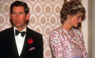 Princess Diana wearing a pink dress and tiara looking away from Prince Charles, wearing a tux