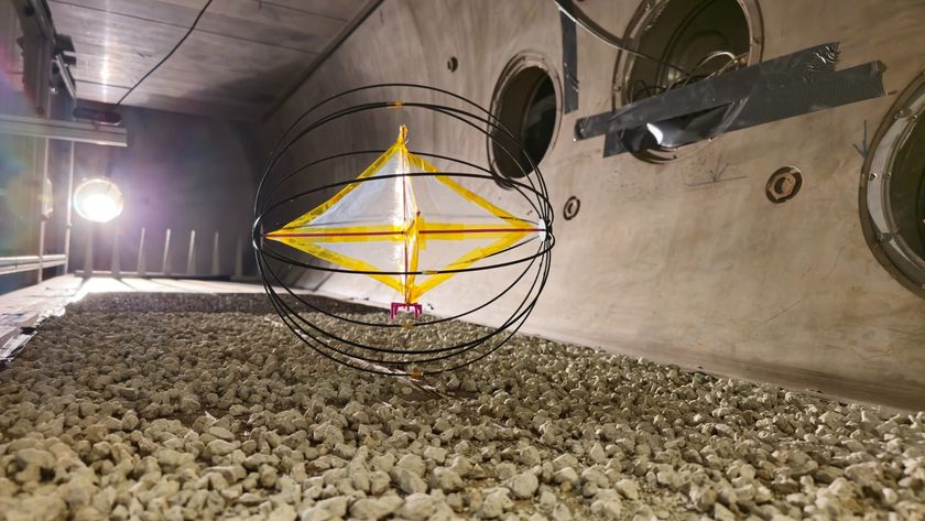 A round cage-like ball encloses a white diamond shape with a yellow outline that rolls over rocks in a dimly lit room.