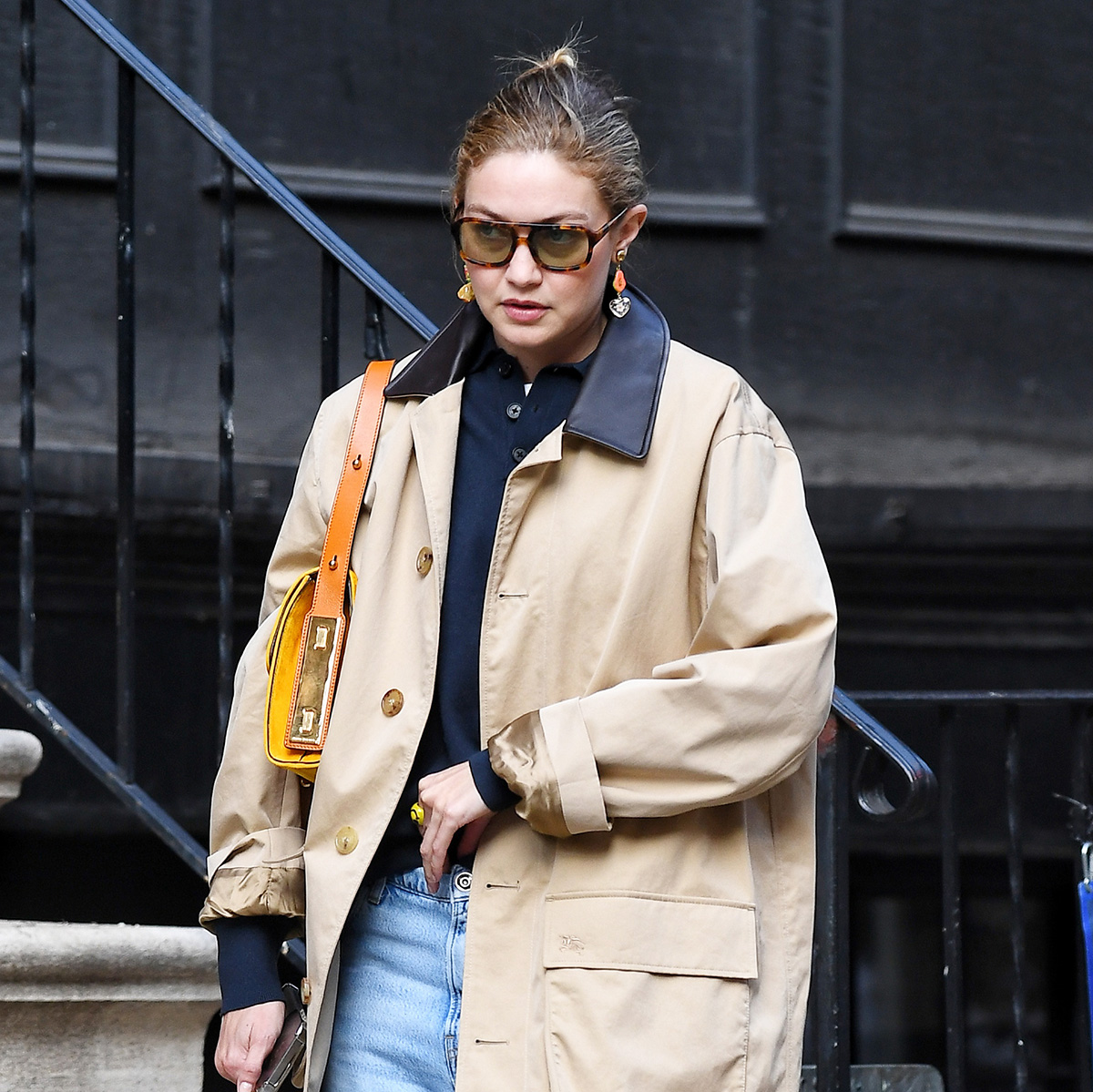 Gigi Hadid wearing a trench, polo top, light-wash jeans, and red Miu Miu loafers