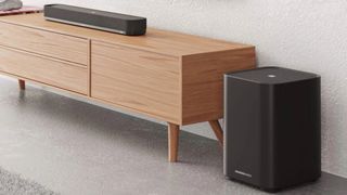 Sennheiser Ambeo Mini-soundbar op een houten meubel met een subwoofer dichtbij