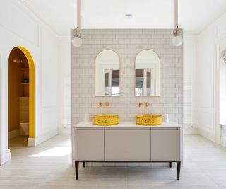 bathroom with two yellow basins on a vanity unit with mirrors and pendant lights above