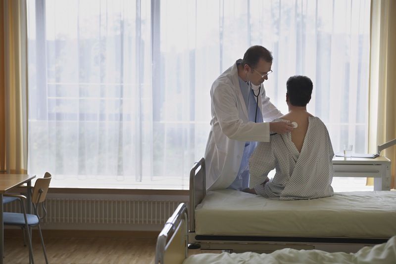 A doctor examines a patient who is wearing a gown.