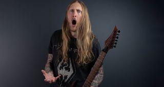 Ola England strikes a pose against a dark gray background. He holds one of his Solar Guitars