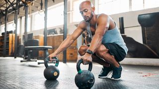 Man holding kettlebells in gym