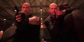 Hobbs & Shaw aiming their guns at a door, bathed in red light